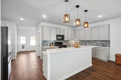 Kitchen featuring a center island with sink, black appliances, and dark hardwood / wood-style floors | Image 3