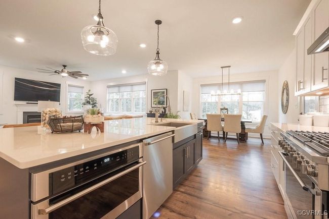 Kitchen with appliances with stainless steel finishes, a ceiling fan, dark wood-type flooring, a chandelier, and light countertops | Image 29