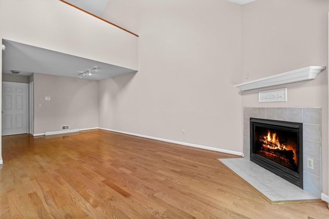 Unfurnished living room with a tile fireplace, light wood-style flooring, baseboards, and rail lighting | Image 6