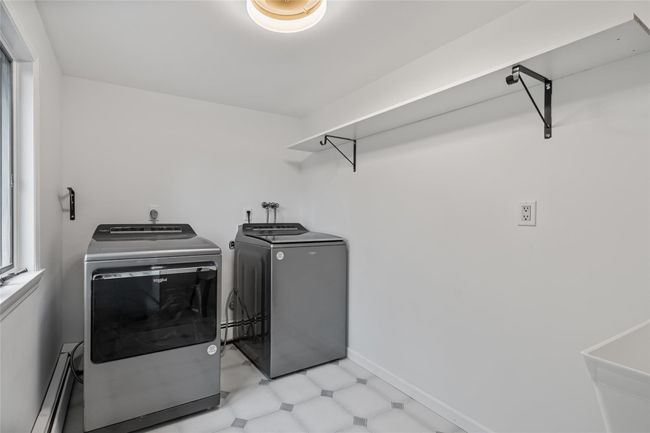 Laundry room featuring baseboard heating, washer and clothes dryer, and light floors | Image 30