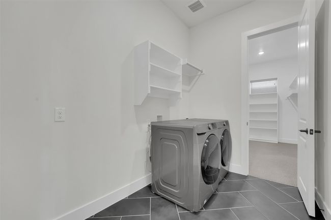 Laundry room featuring washing machine and clothes dryer, baseboards, visible vents, dark tile patterned flooring, and laundry area | Image 22