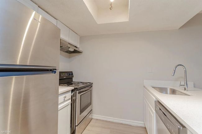 Kitchen featuring stainless steel appliances, under cabinet range hood, light countertops, and light wood-style floors | Image 5