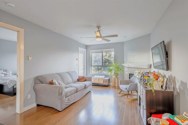 Living area featuring baseboards, light wood finished floors, a brick fireplace, and a ceiling fan | Image 9