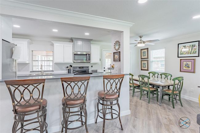 Kitchen with a kitchen breakfast bar, range with electric cooktop, crown molding, sink, and white cabinetry | Image 23