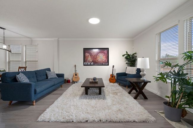 Living area featuring ornamental molding, baseboards, a notable chandelier, and wood finished floors | Image 7