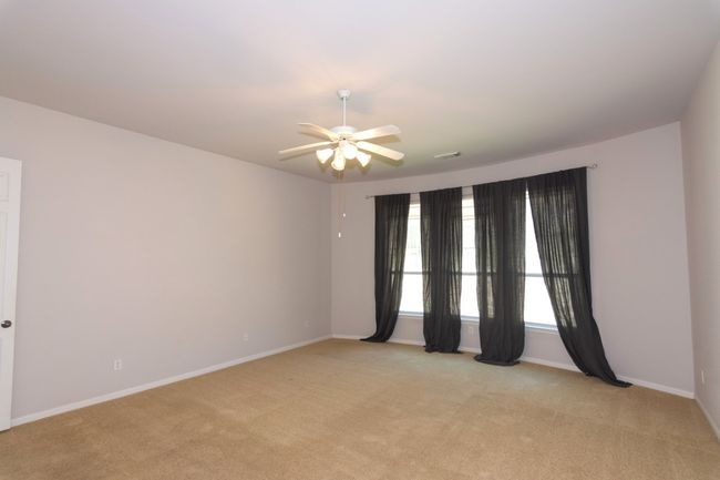 Unfurnished room featuring light colored carpet, ceiling fan, baseboards, and visible vents | Image 11