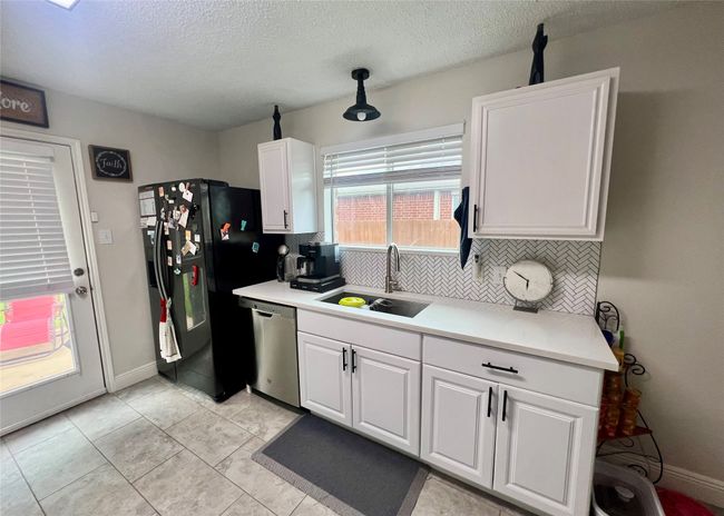Kitchen featuring a sink, dishwasher, black fridge, tasteful backsplash | Image 9