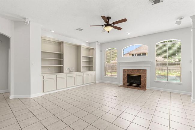 The family room has arched windows, a fireplace, and a wall of built-ins to display your collectibles and books. | Image 15