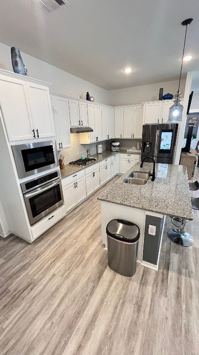 Kitchen featuring a sink, appliances with stainless steel finishes, light wood-style flooring, white cabinets, and a kitchen island with sink | Image 11