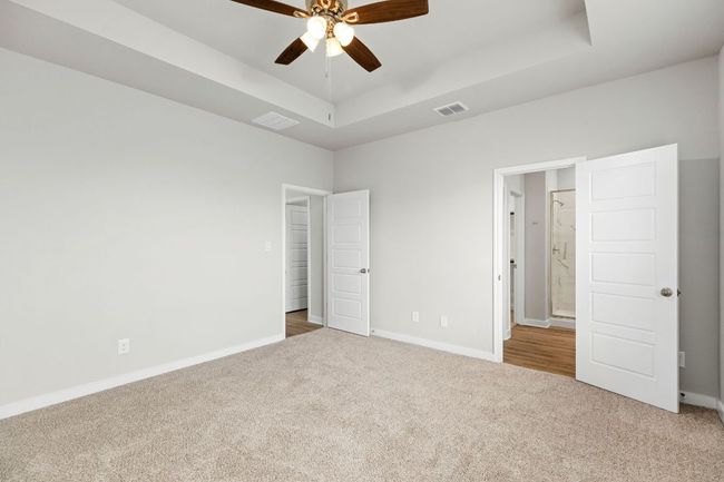 Unfurnished bedroom with carpet floors, a raised ceiling, visible vents, and baseboards | Image 22
