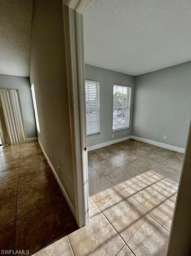 Hall with tile patterned flooring, a textured ceiling, and baseboards | Image 5