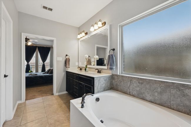 Ensuite bathroom with a bath, a sink, tile patterned flooring, and visible vents | Image 20
