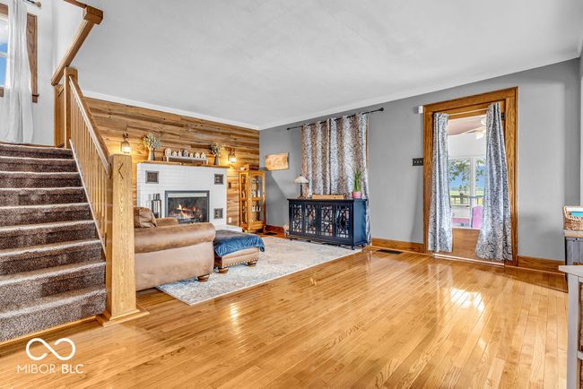 living room with wood-type flooring, stairs, and a lit fireplace | Image 17
