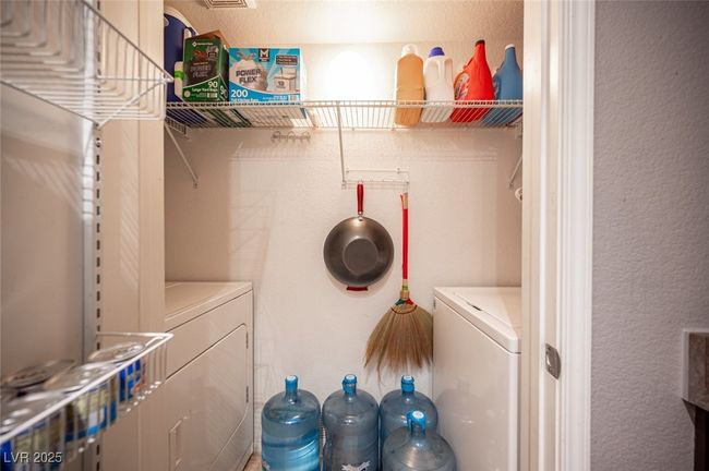 Washroom featuring a textured wall, washing machine and dryer, and laundry area | Image 29