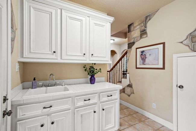 A convenient mud area near the garage entrance features direct access to the outdoors. Tiled countertop, 13" deep sink and storage cabinetry make this area a durable transition space to clean up or contain exterior elements before stepping into the heart of the home. | Image 24