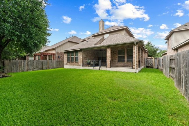 Back of property featuring brick siding, roof with shingles, a chimney, and a fenced backyard | Image 39