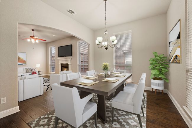 Dining area featuring wood finished floors, baseboards, ceiling fan, a chandelier, and a lit fireplace | Image 10