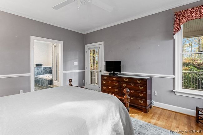 Bedroom with multiple windows, wood finished floors, ornamental molding, ensuite bathroom, and ceiling fan | Image 30