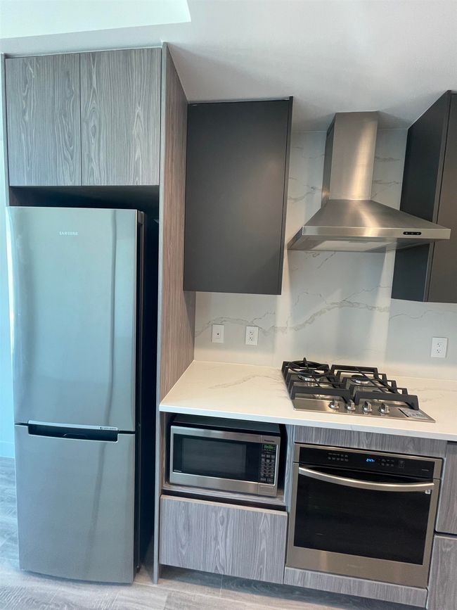 Kitchen featuring wall chimney range hood, gray cabinetry, stainless steel appliances, and modern cabinets | Image 8