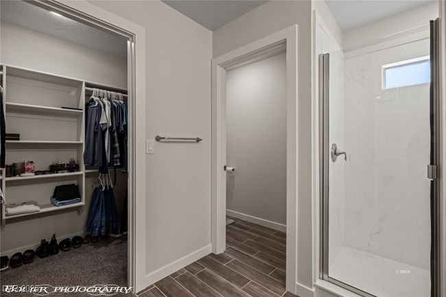 Bathroom featuring a stall shower, a spacious closet, baseboards, and wood finished floors | Image 40