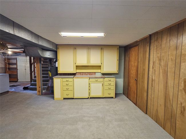 Finished basement featuring wood walls, water heater, stairs, and light carpet | Image 25