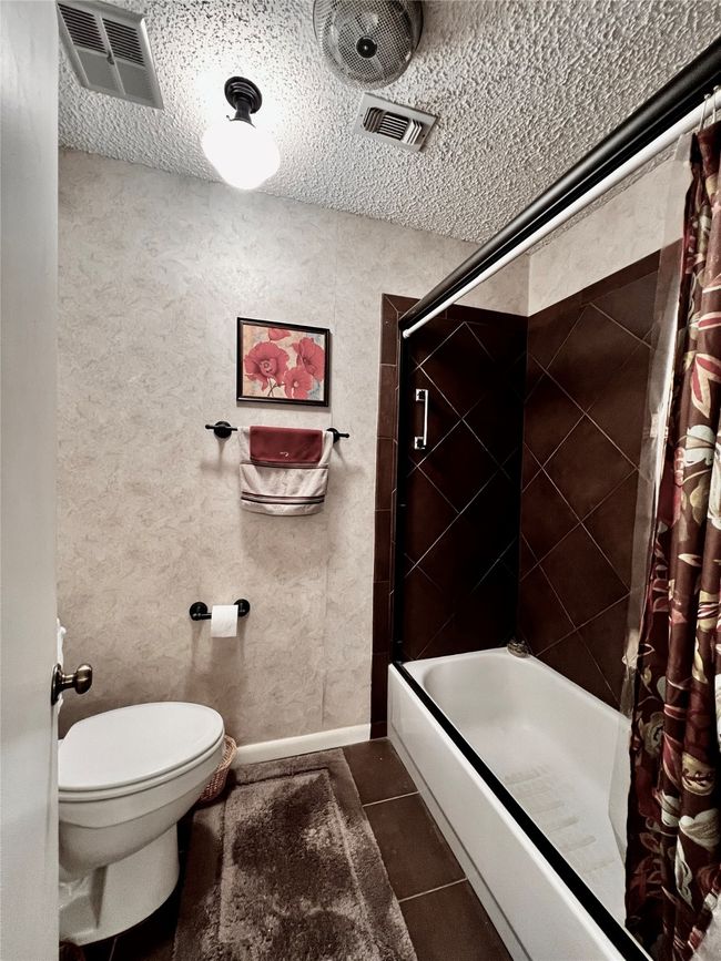 Bathroom featuring shower / bath combo, a textured ceiling, toilet, and tile patterned floors | Image 13