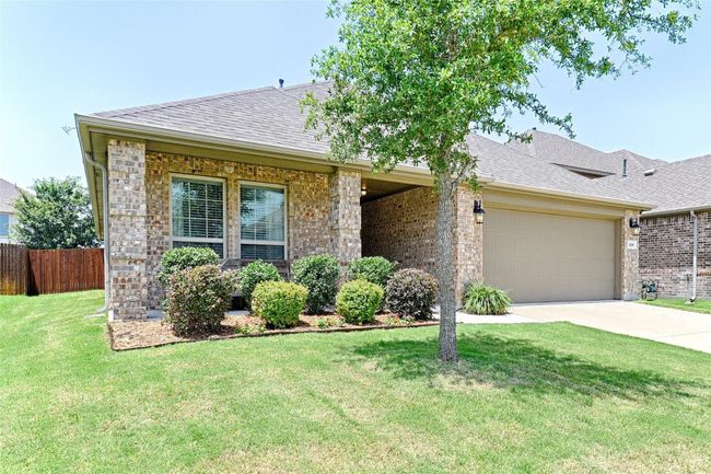 View of front of property featuring concrete driveway, roof with shingles, an attached garage, and brick siding | Image 22