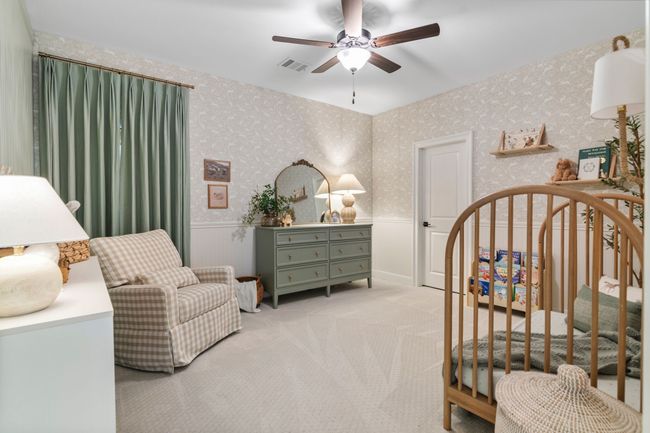 Carpeted bedroom with a wainscoted wall, a nursery area, ceiling fan, and wallpapered walls | Image 33