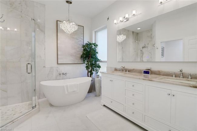 Full bathroom featuring a notable chandelier, a shower stall, and a sink | Image 15