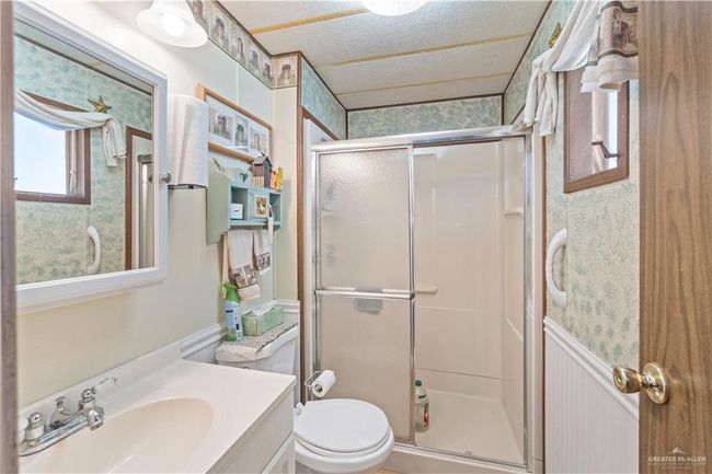 Full bathroom with a stall shower, vanity, toilet, and wallpapered walls | Image 11