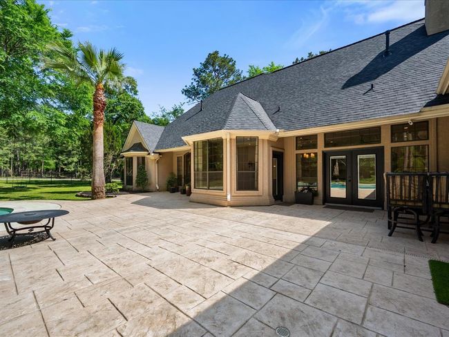 Step outside to the private backyard oasis with stamped concrete patio, lush landscaping, and peaceful tree-lined views. | Image 35