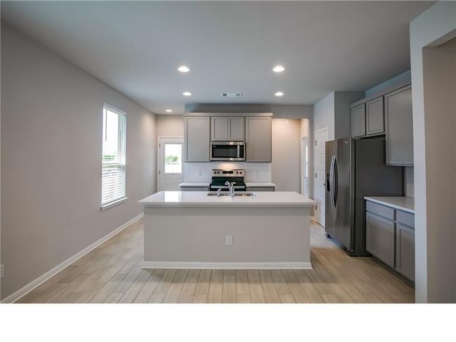 Kitchen featuring appliances with stainless steel finishes, a center island with sink, gray cabinetry, recessed lighting, and backsplash | Image 8