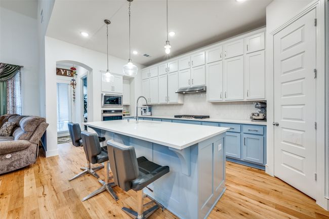 Kitchen with stainless steel appliances, light countertops, decorative backsplash, arched walkways, and a breakfast bar area | Image 9