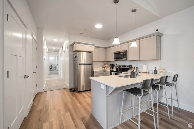 Kitchen with a peninsula, baseboards, light wood-style floors, light countertops, and appliances with stainless steel finishes | Image 7