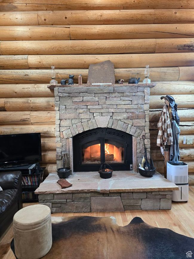 Interior details featuring rustic walls, a stone fireplace, and wood finished floors | Image 67