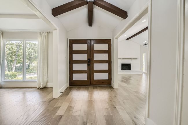 Entrance foyer with baseboards, lofted ceiling with beams, a fireplace with raised hearth, and light wood finished floors | Image 4