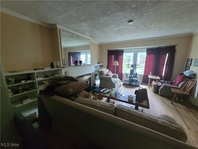 Living room featuring hardwood / wood-style floors, crown molding, and a textured ceiling | Image 2