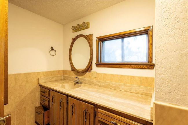 Kitchen featuring a sink, brown cabinets, light countertops, a ceiling fan, and a textured ceiling | Image 25