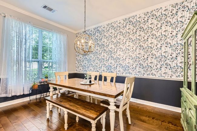 Dining space with wallpapered walls, a wainscoted wall, a chandelier, crown molding, and hardwood flooring | Image 7