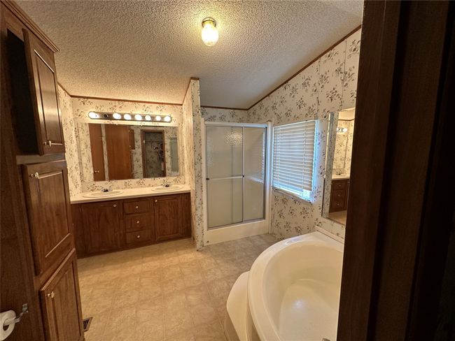 Bathroom featuring wallpapered walls, vaulted ceiling, a stall shower, a textured ceiling, and a garden tub | Image 23