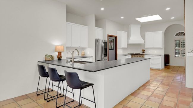 Kitchen with a peninsula, a sink, stainless refrigerator, 36" gas range, and crafted range hood | Image 12