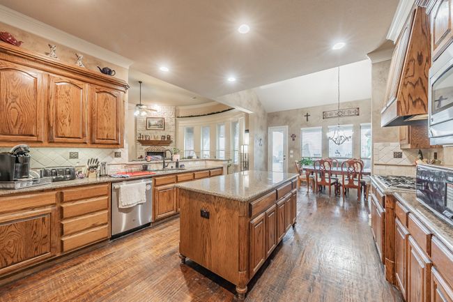 Kitchen featuring stainless steel appliances, dark wood-style flooring, brown cabinets, hanging light fixtures, and recessed lighting | Image 17