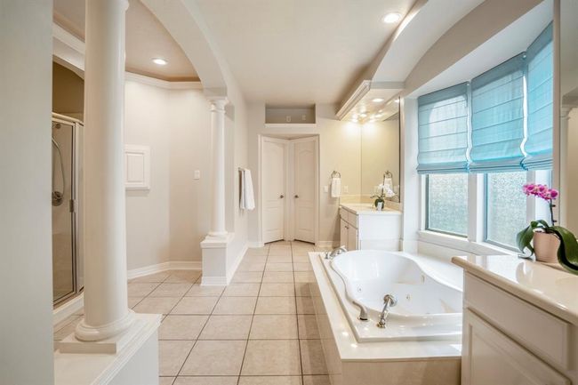 Columns elevate the primary bathroom suite to spa like status, with a large whirlpool tub nestled under three large arched defused windows. | Image 22