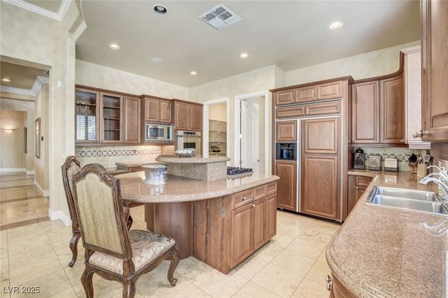 Kitchen featuring a sink, built in appliances, crown molding, visible vents, and a kitchen island | Image 19