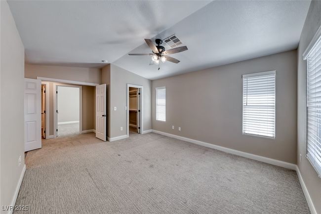 Unfurnished bedroom featuring light carpet, vaulted ceiling, a walk in closet, ceiling fan, and a closet | Image 19