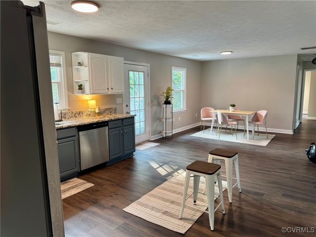 Kitchen with stainless steel dishwasher, a textured ceiling, open shelves, gray cabinets, and dark wood-style flooring | Image 13