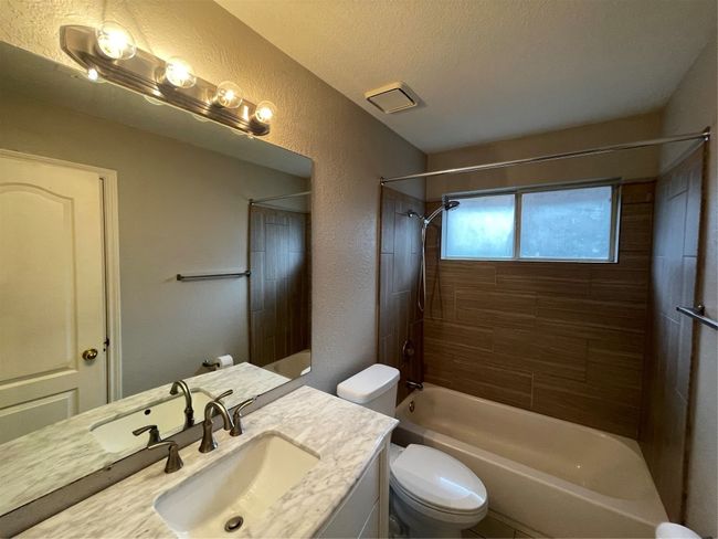 Bathroom featuring vanity, shower / washtub combination, a textured wall, and a textured ceiling | Image 16