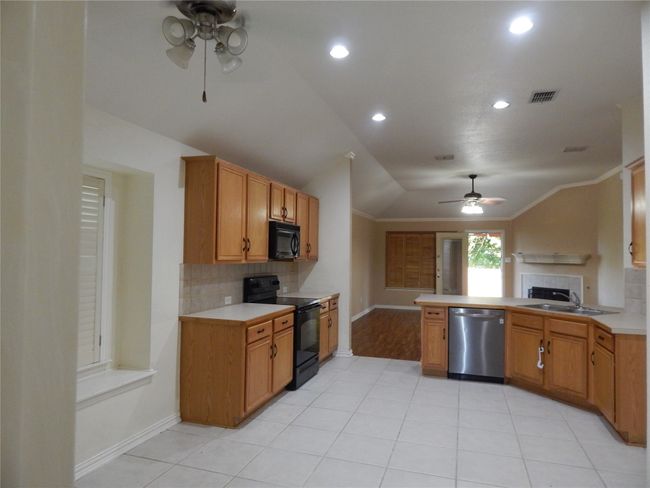 Kitchen with black appliances, ceiling fan, lofted ceiling, a peninsula, and tasteful backsplash | Image 4