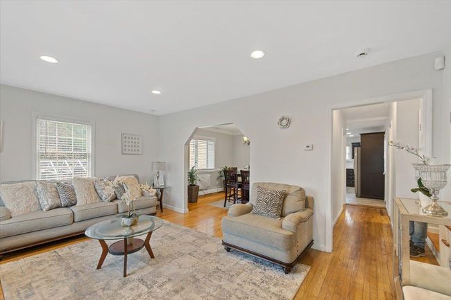 Living area with light wood-style flooring, arched walkways, baseboards. | Image 24