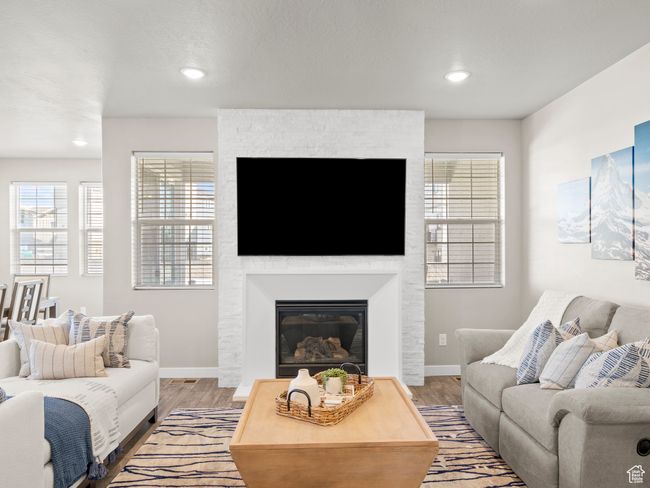 Living room with wood finished floors, a large fireplace, and recessed lighting | Image 7